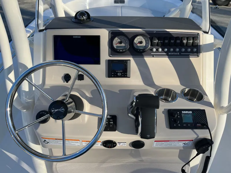 Slide: The Image of 2025 Boston Whaler 210 Montauk boat dashboard with steering wheel and navigation controls. - 3