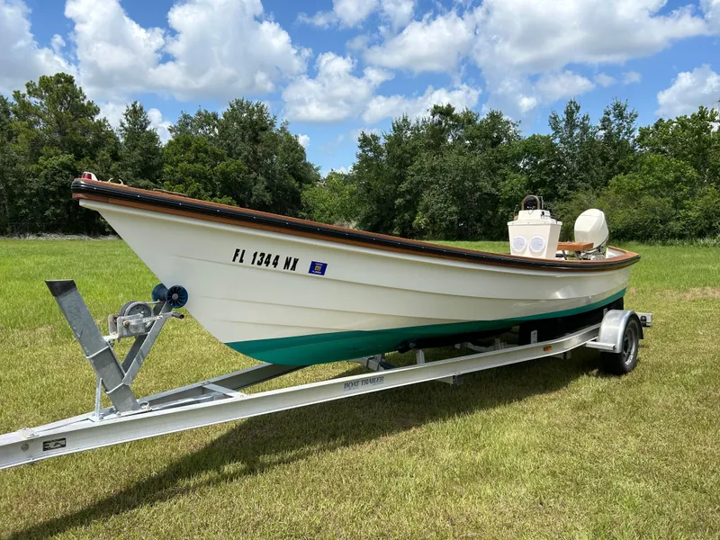 The Image of 2005 Caribiana Skiff boat on trailer, parked on grassy field under blue sky. - 1