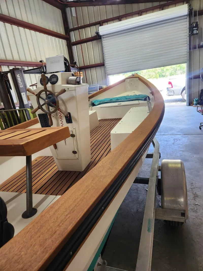 Slide: The Image of 2005 Caribiana Skiff boat in a garage, featuring wooden deck and steering console. - 10
