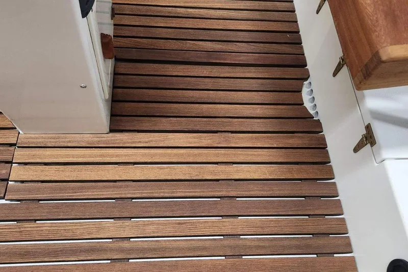 Slide: The Image of Teak deck of 2005 Caribiana Skiff boat, showcasing wooden slats and white interior elements. - 12