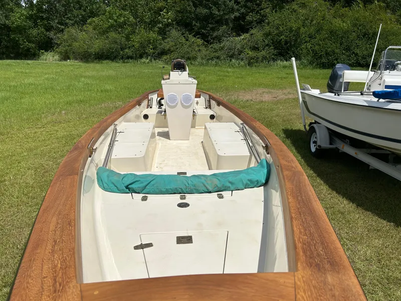 Slide: The Image of 2005 Caribiana Skiff boat on grass, featuring wooden trim and central console. - 7