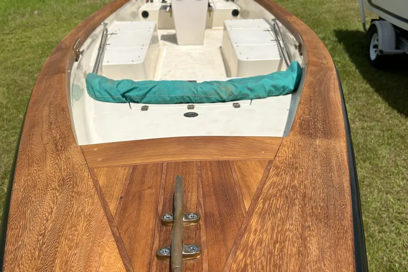 Slide: The Image of 2005 Caribiana Skiff boat with wooden deck and teal seating, displayed on grass. - 9