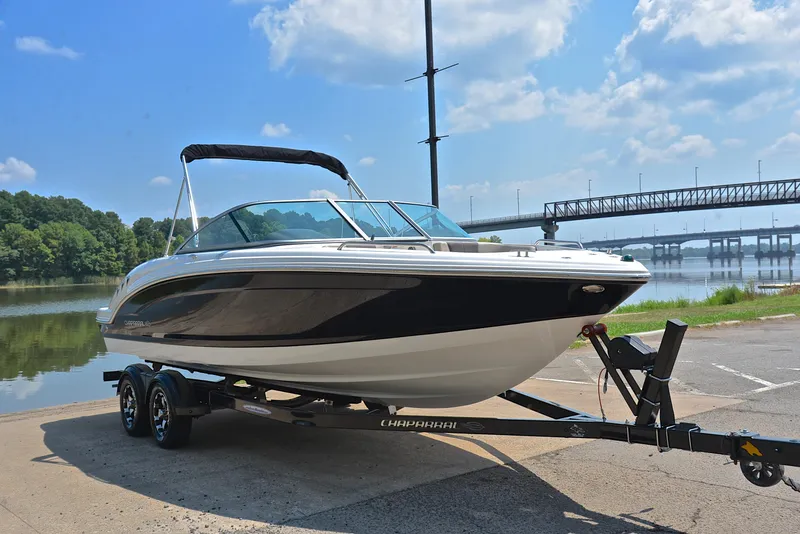 Slide: The Image of 2019 Chaparral 23 H20 boat on trailer by river, under blue sky. - 16
