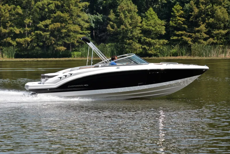 Slide: The Image of 2019 Chaparral 23 H20 boat cruising on a lake with lush green trees. - 3
