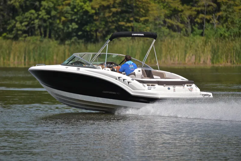Slide: The Image of 2019 Chaparral 23 H20 speedboat cruising on a lake with lush greenery. - 4