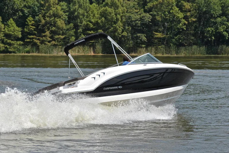 Slide: The Image of 2019 Chaparral 23 H20 speedboat cruising on a lake with lush green trees. - 5