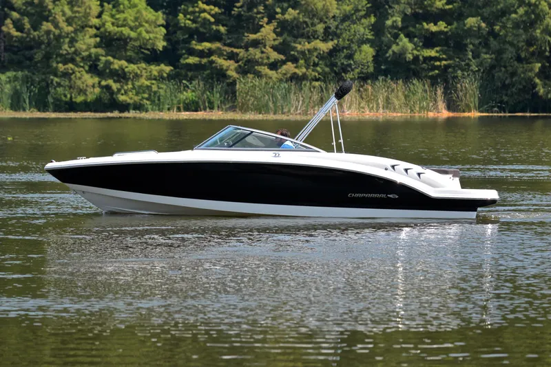 Slide: The Image of 2019 Chaparral 23 H20 boat cruising on a calm lake with forested background. - 9