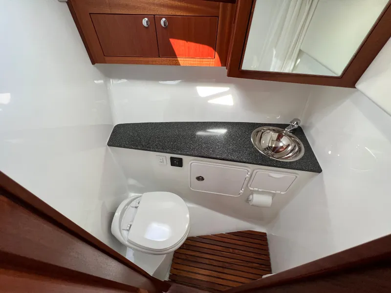 Slide: The Image of 2022 Ocean Sport 30 Roamer boat bathroom with sink, toilet, and wooden flooring. - 13
