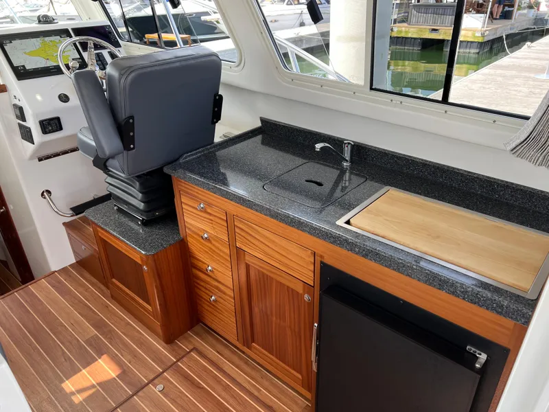 Slide: The Image of Interior of 2022 Ocean Sport 30 Roamer with helm seat, kitchenette, and wood flooring. - 14