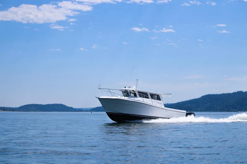 Slide: The Image of Ocean Sport 30 Roamer 2022 cruising on a serene lake under a clear blue sky. - 18