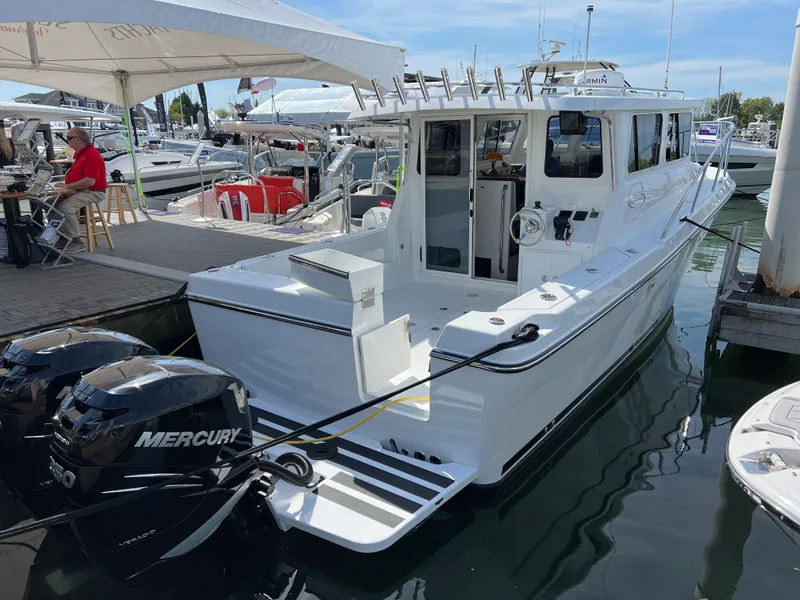 Slide: The Image of 2022 Ocean Sport 30 Roamer boat docked with twin Mercury engines. - 2