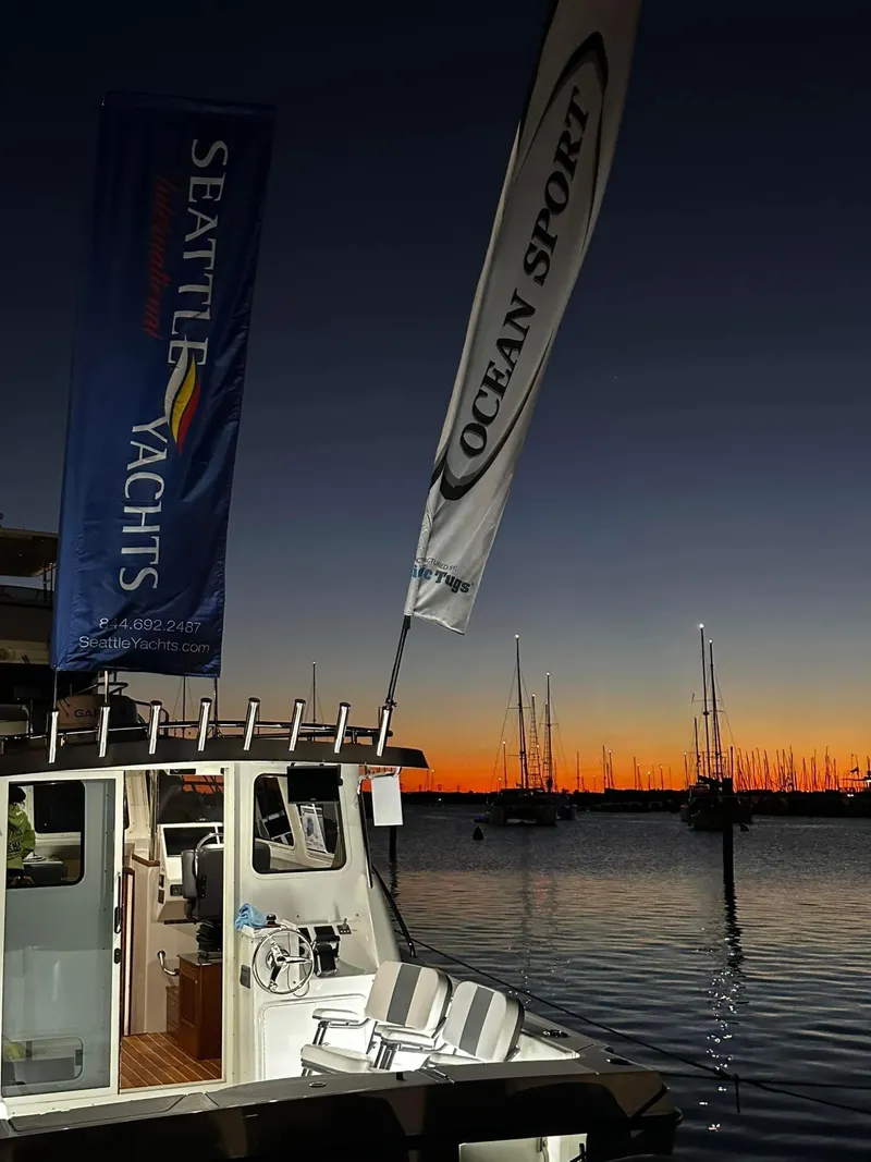Slide: The Image of 2022 Ocean Sport 30 Roamer at sunset marina with Seattle Yachts banner. - 4