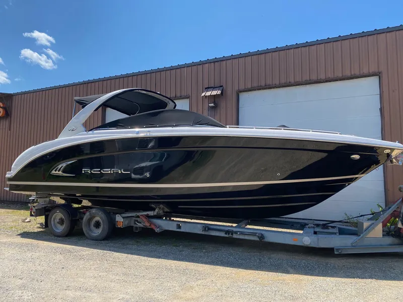 Slide: The Image of 2013 Regal 3200 Bowrider boat on trailer, parked outside a warehouse. - 3
