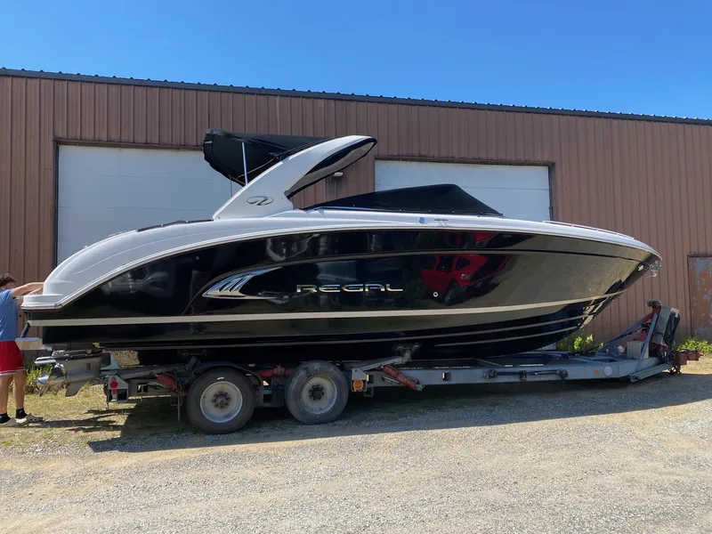 Slide: The Image of 2013 Regal 3200 Bowrider boat on trailer, black and white design, parked outdoors. - 6
