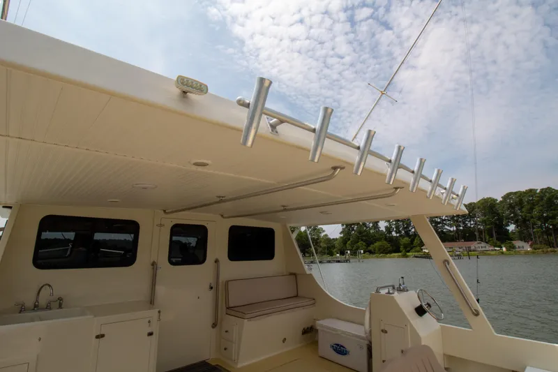 Slide: The Image of 2008 Chesapeake 48 Deadrise boat interior with seating and rod holders, docked by a scenic lake. - 19