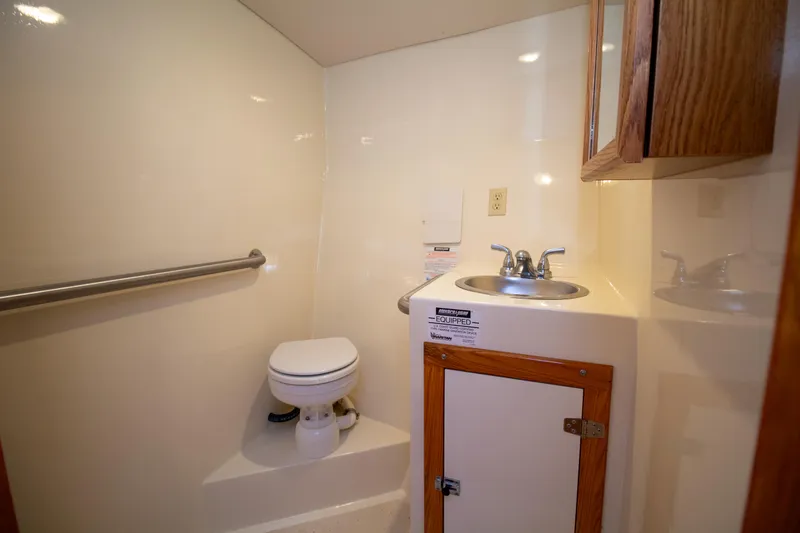 Slide: The Image of 2008 Chesapeake 48 Deadrise boat bathroom with toilet, sink, and wooden cabinet. - 4