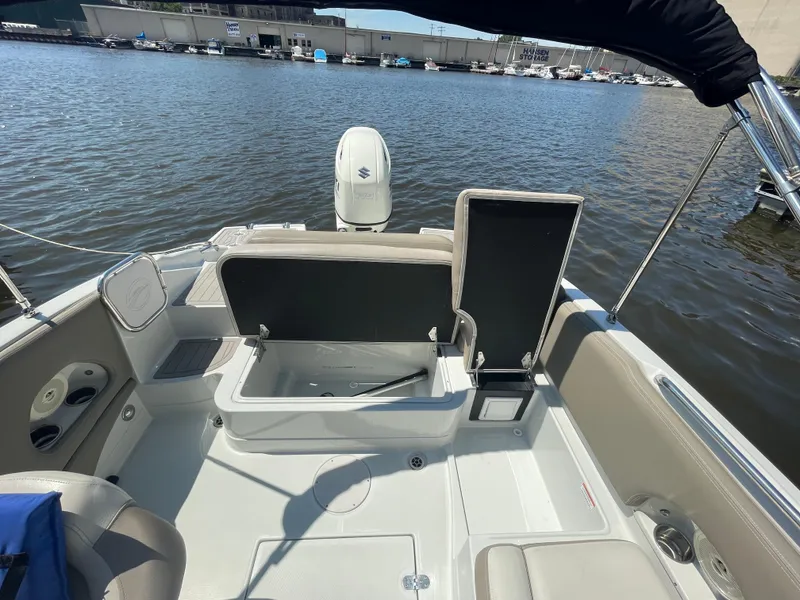 Slide: The Image of 2020 Crownline E 205 XS boat interior with open storage, docked by the water. - 10