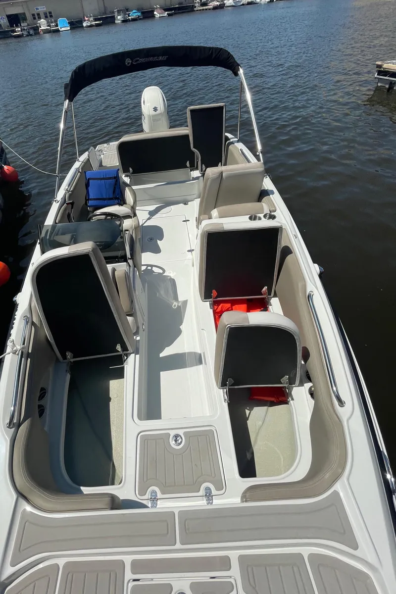 Slide: The Image of 2020 Crownline E 205 XS boat with spacious seating, docked on calm water. - 18