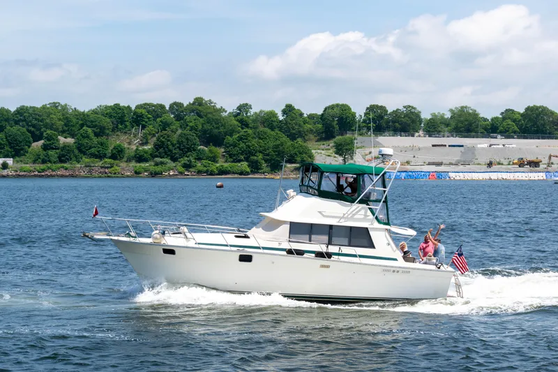 Slide: The Image of 1981 Silverton 37 Convertible boat cruising on a sunny day with passengers waving. - 0