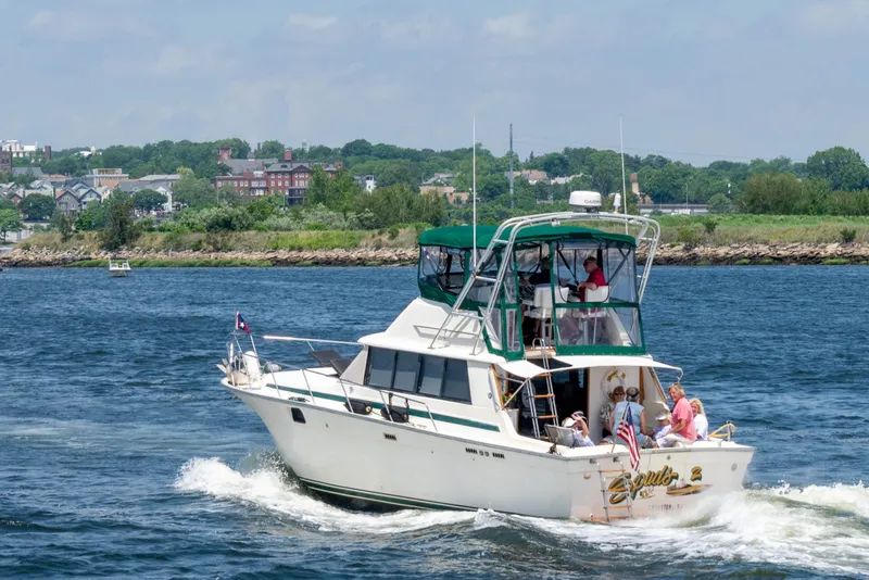 Slide: The Image of 1981 Silverton 37 Convertible boat cruising on a scenic waterway with passengers onboard. - 1
