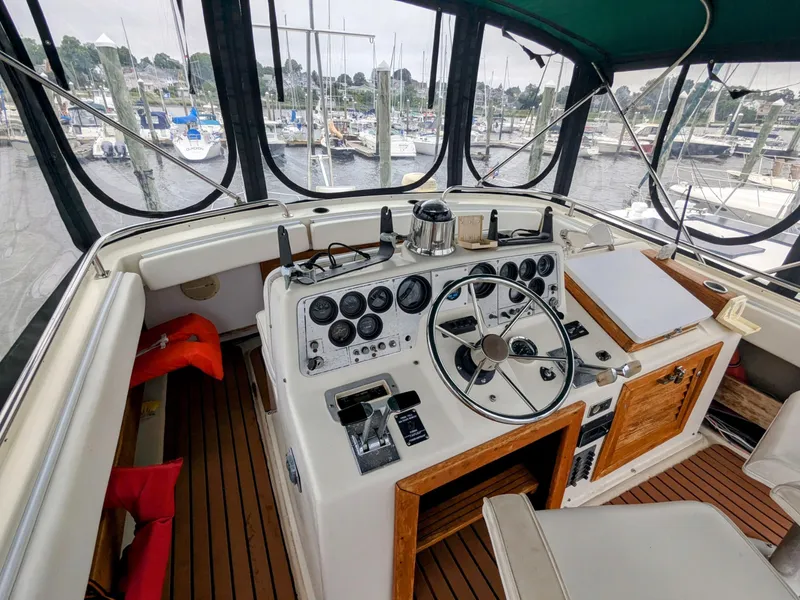 Slide: The Image of 1981 Silverton 37 Convertible boat cockpit with steering wheel and control panel at marina. - 10