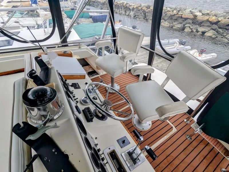 Slide: The Image of 1981 Silverton 37 Convertible boat helm with dual white captain chairs and wooden deck. - 11