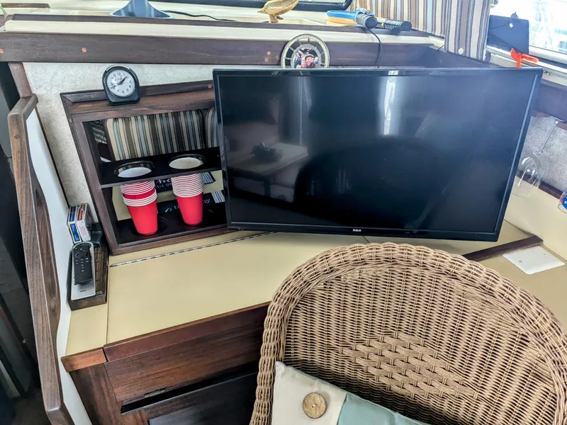 Slide: The Image of 1981 Silverton 37 Convertible interior with TV, wicker chair, and red cups on a shelf. - 22