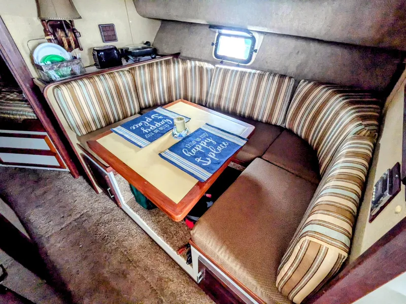 Slide: The Image of Cozy dining area in 1981 Silverton 37 Convertible boat with striped seating and nautical decor. - 24