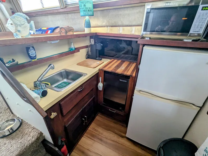 Slide: The Image of 1981 Silverton 37 Convertible boat kitchen with sink, fridge, microwave, and wooden countertops. - 26