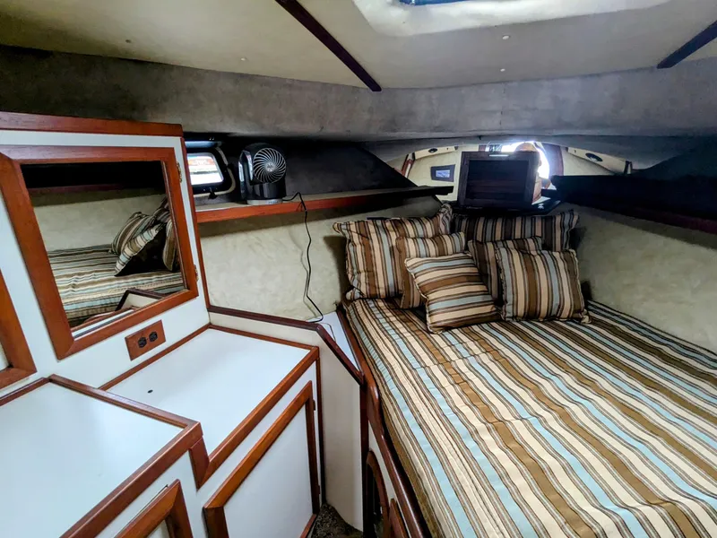 Slide: The Image of 1981 Silverton 37 Convertible cabin with striped bedding and wooden cabinetry. - 30