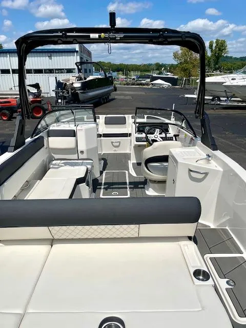 Slide: The Image of 2021 Bayliner DX 2250 boat interior with seating and steering wheel, docked outdoors. - 6
