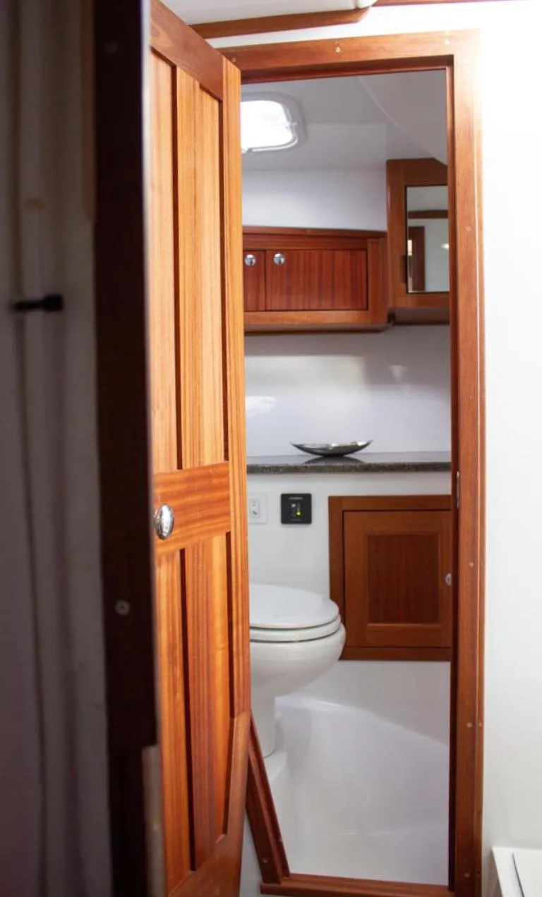 Slide: The Image of Interior of 2022 Ocean Sport 30 Roamer, featuring wooden cabinetry and compact bathroom. - 21