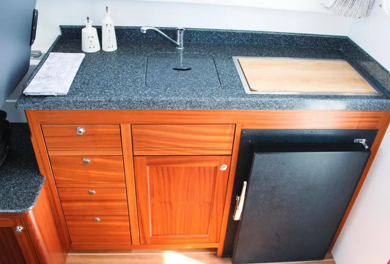 Slide: The Image of Luxurious kitchen area in 2022 Ocean Sport 30 Roamer, featuring wood cabinetry and granite countertop. - 8