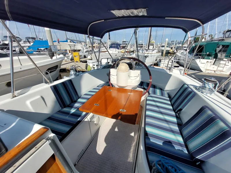 Slide: The Image of 2002 Beneteau Oceanis 42CC sailboat cockpit with striped seating and wooden table in marina. - 23