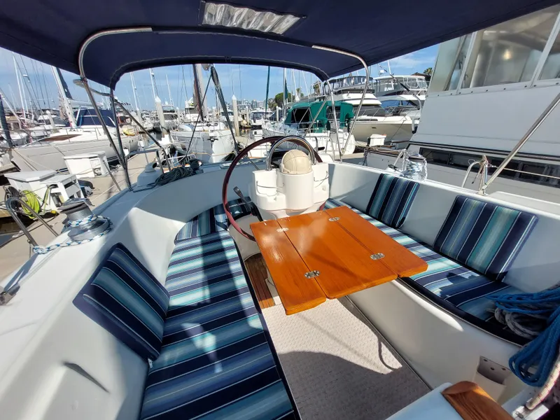 Slide: The Image of Beneteau Oceanis 42CC 2002 sailboat cockpit with striped seating and wooden table in marina. - 24