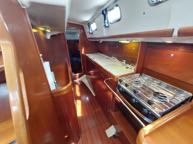 Slide: The Image of Interior of 2002 Beneteau Oceanis 42CC sailboat with wooden cabinetry and compact kitchen. - 42