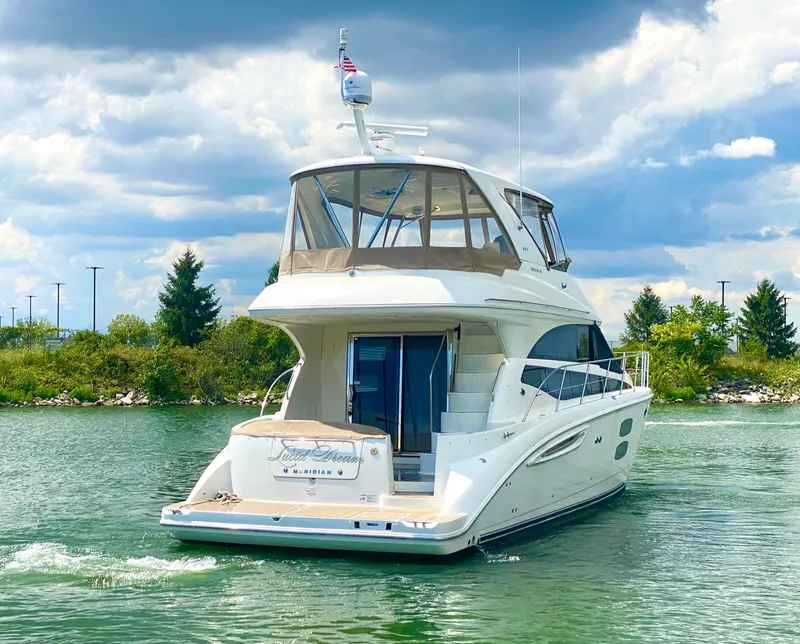 Slide: The Image of 2014 Meridian 441 Sedan yacht cruising on a serene lake under a cloudy sky. - 5