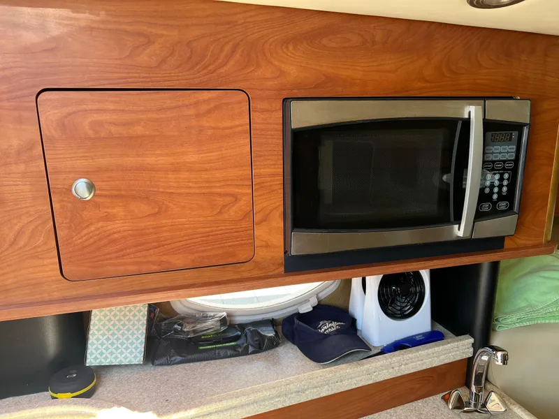 Slide: The Image of 2008 Rinker 260 Express Cruiser interior with microwave and storage cabinet. - 16