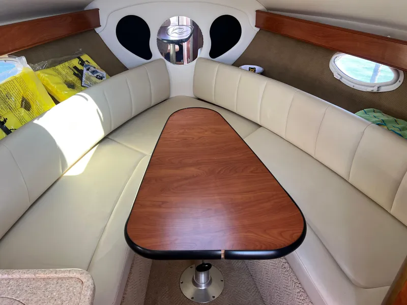 Slide: The Image of 2008 Rinker 260 Express Cruiser cabin with wood table and beige seating. - 22