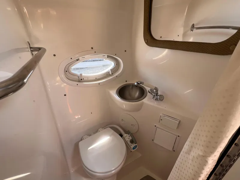 Slide: The Image of 2008 Rinker 260 Express Cruiser bathroom with toilet, sink, and porthole window. - 25