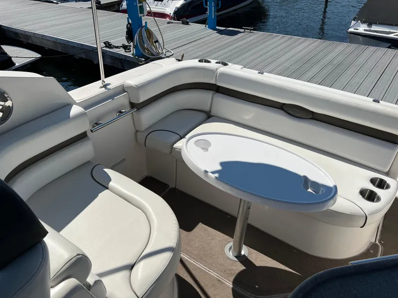 Slide: The Image of 2008 Rinker 260 Express Cruiser interior with white seating and table at dock. - 4