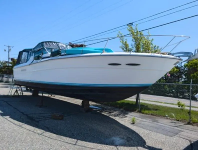Slide: The Image of 1989 Sea Ray 390 Express Cruiser on dry dock, white hull, blue accents, sunny day. - 1