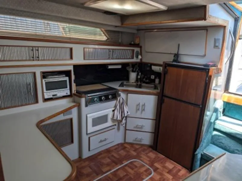 Slide: The Image of 1989 Sea Ray 390 Express Cruiser kitchen with stove, microwave, and fridge. - 12