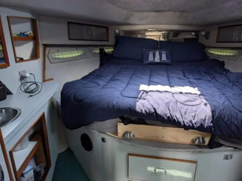 Slide: The Image of 1989 Sea Ray 390 Express Cruiser cabin with cozy bed and compact sink area. - 14