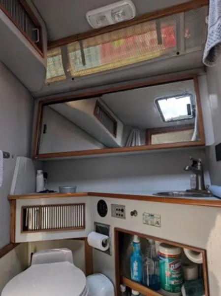 Slide: The Image of 1989 Sea Ray 390 Express Cruiser bathroom with mirror, sink, and storage shelves. - 17