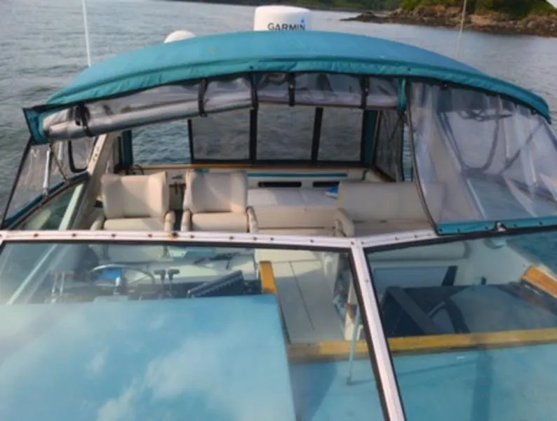 Slide: The Image of 1989 Sea Ray 390 Express Cruiser with blue canopy on calm water. - 5