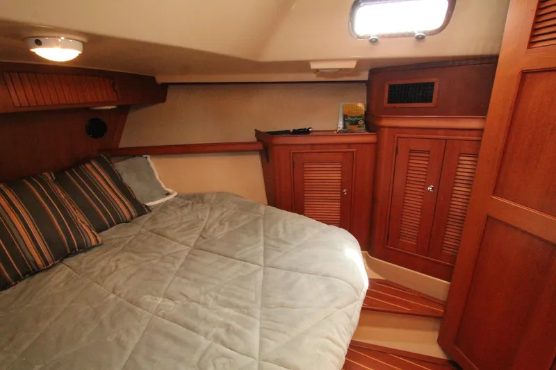 Slide: The Image of Island Packet 360 yacht cabin, 2002 model, featuring cozy bed and wooden cabinets. - 21