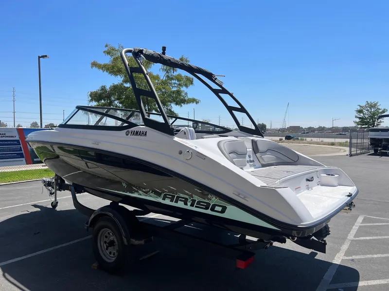 Slide: The Image of 2023 Yamaha AR 190 jet boat on trailer, parked outdoors under clear blue sky. - 8