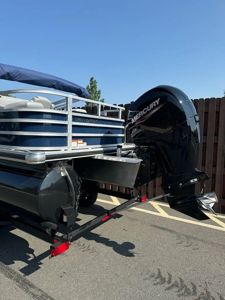 Slide: The Image of 2024 Ranger Reata 220F pontoon boat with Mercury outboard motor, parked outdoors. - 2