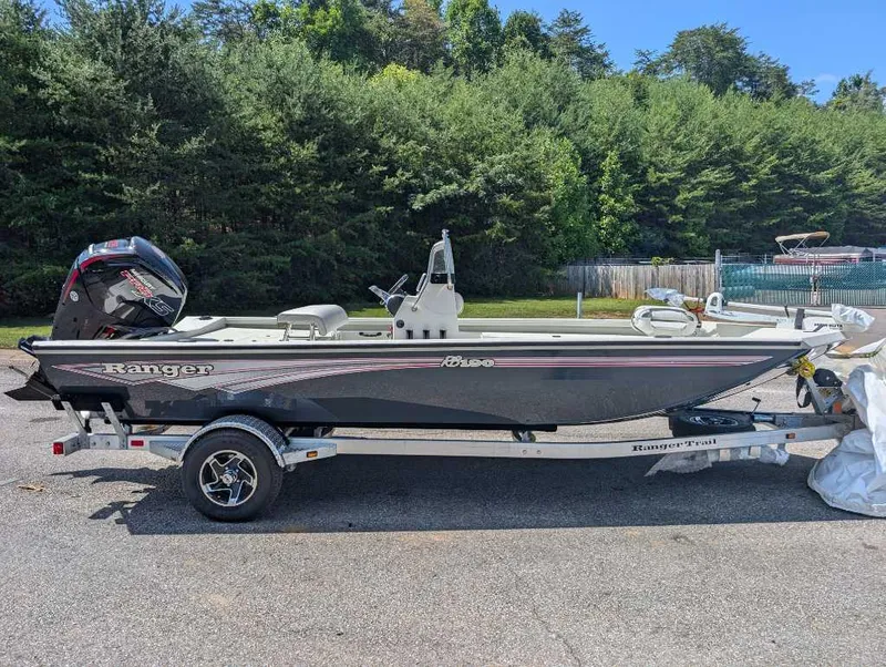 Slide: The Image of 2024 Ranger RB190 boat on trailer, parked outdoors with trees in background. - 0